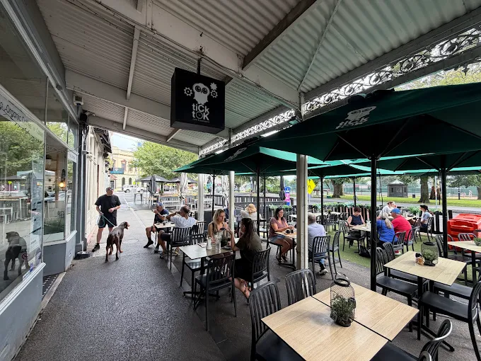 Patrons dining on the Tick Tok street-side patio with branded green umbrellas